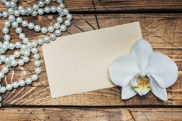 Orchid flower, beads and a form for text on a wooden table. Concept romance mood. Copy space and...