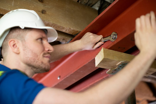 Construction Worker Fitting Steel Support Beam Into Renovated House Ceiling