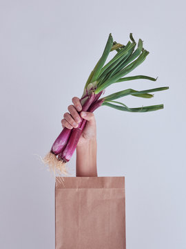 Person hand reached out from packet and holding red leek