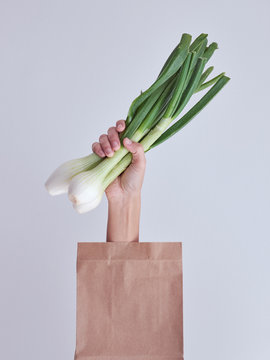 Person hand reached out from packet and holding leek