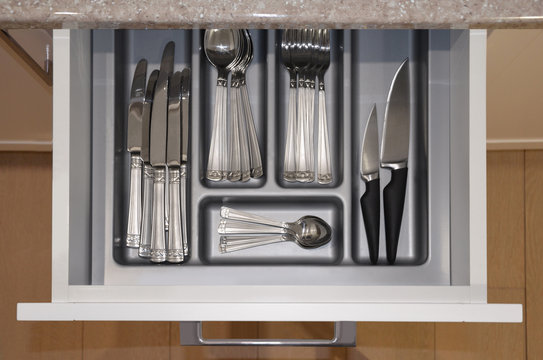 Opened kitchen drawer with a tray and cutlery set  inside. View from above. Image