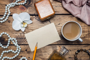 Orchid flower and accessories, cup of coffee a form for text on a wooden table. Concept romance mood. Copy space and flat lay