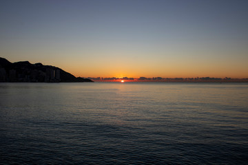 Beautiful morning sunrise over the sea showing yellow sun with a few clouds in the background, taken in Spain Costa Brava near Alicante and Benidorm 