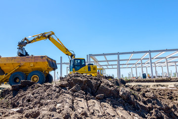 Excavator is loading a truck with ground on building site