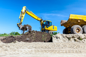Obraz premium Excavator is loading a truck with ground on building site