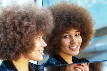 Young, smiling woman with afro hair looking in a mirror
