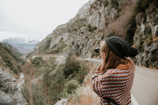 Young woman shooting on camera between mountains