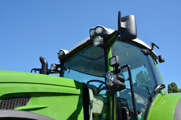 Modern tractor cabin. New green tractor with headlights.