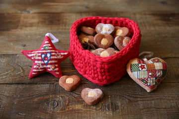 heart shaped cookie in a red basket in the shape of a heart decorative star and heart on a wooden background
