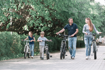 Obraz premium modern family with their bikes walk through the city Park