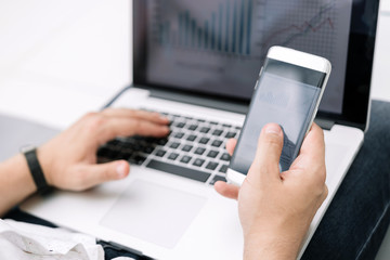 close up. the businessman uses a smartphone and a laptop in the workplace.