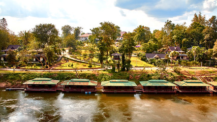 Many wooden house floating on the river with mountain at Float house river kwai resort, Kanchanaburi, Thailand
