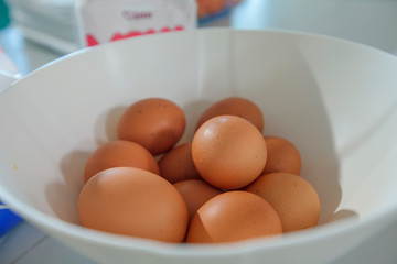 There are eggs in a white bowl. Children are having a cooking class.