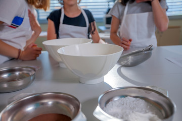 Kids are ready to start a cooking class. All the bowls are ready on the table.