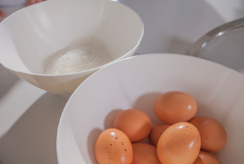 There are eggs in one bowl and flour is in the other.