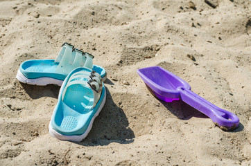 Fototapeta na wymiar Baby scoop and slippers in the sand