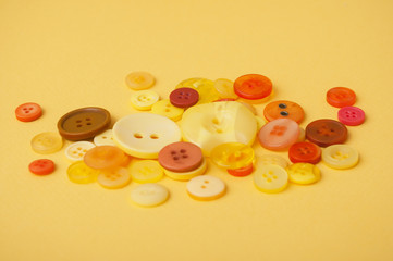 closeup of yellow and orange sewing plastic buttons on yellow background