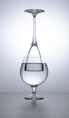 two drinking glasses with water  light  background, concept design, optic illusion
