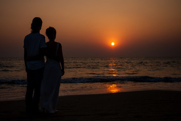 male making proposal with engagement ring to his girlfriend at sea beach.St.Valentines Day concept.beautiful woman in white dress and man enjoying the sunset on the sea