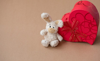 Present for the Valentine's day. Red gift box and red ribbon with tag on brown wooden board background with space for text.