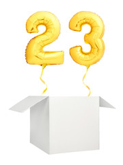 Golden number twenty three inflatable balloon with golden ribbon flying out of blank white box isolated on white background