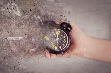 Time is running out concept. The clock breaks down into pieces. Hand holding analog clock with...