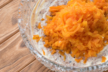 The process of cooking fish salad Mimosa. Laying carrots and mayonnaise