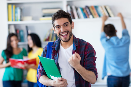 Jubelnder spanischer Student in der Uni-Bibliothek