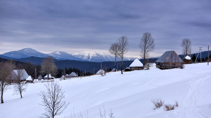 Fototapeta premium Panoramic view of idyllic winter mountain tops and traditional mountain huts in the Carpathians