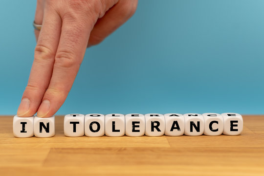 Tolerance instead of intolerance. Dice form the word intolerance, while the letters "IN" where pushed away by a finger