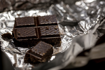 Macro photo of dark chocolate pieces in foil wrapper.