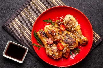 The concept of Japanese and Chinese cuisine. Chicken fried legs with hot pepper, sesame, chuka salad, Chinese peas on black table. Asian dish. top view, flat lay