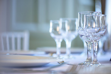 Clean table setting for fine dining with focus on two crystal glasses for water and wine, ready for guests at an event, wedding or at a restaurant, horizontal perspective with shallow depth of field