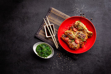 The concept of Japanese and Chinese cuisine. Chicken fried legs with hot pepper, sesame, chuka salad, Chinese peas on black table. Asian dish. top view, flat lay