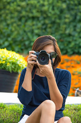 Hand woman holding the camera Taking pictures Background of trees and flowers