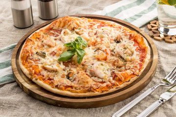 Pizza with seafood, mozzarella, mussels, octopus, squid, salmon, shrimp serves on the table