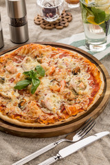 Pizza with seafood, mozzarella, mussels, octopus, squid, salmon, shrimp serves on the table
