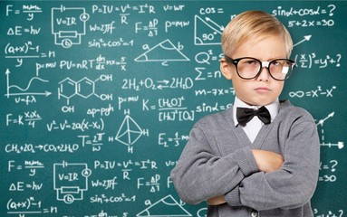 Cute little schoolgirl in glasses on blackboard background