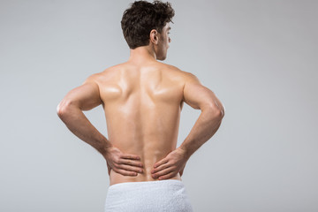 rear view of man suffering from back pain, isolated on grey