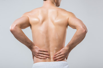 Fototapeta na wymiar rear view of man having back pain, isolated on grey
