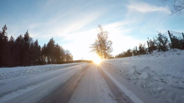 Rising sun dazzling drivers. Dangerous situation from traffic on snowy road in National park Sumava. Czech Republic.