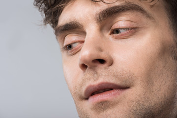 close up of handsome man looking aside isolated on grey