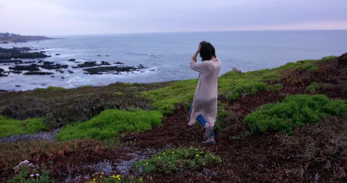 Young trendy woman walking on path towards ocean lookout
