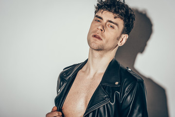 Obraz premium handsome sexy shirtless man posing in black leather jacket on grey
