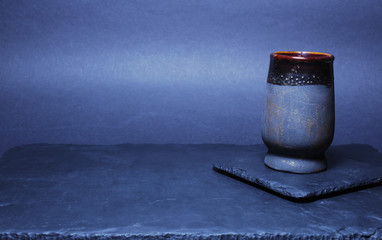 Naklejka premium View directly on the black slate plate and the cup holder on which there is a black ceramic cup. Copy space