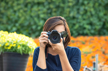 Hand woman holding the camera Taking pictures Background of trees and flowers