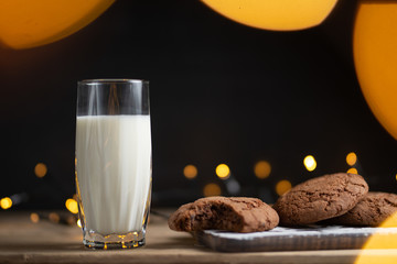 Photo glass of milk with homemade cookies, beautiful background with lights in blur