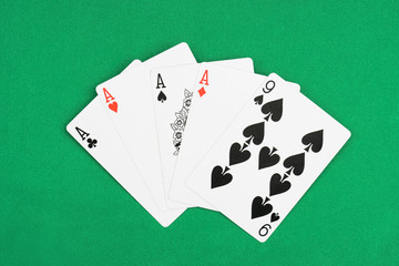 top view of green poker table with unfolded playing cards, four aces and nine