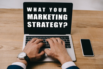 cropped view of businessman typing on laptop with what your marketing strategy?