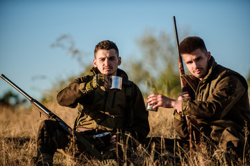 Hunters satisfied with catch drink warming beverage. Rest for real men concept. Hunters with rifles...